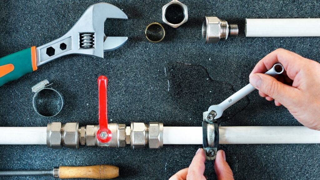 Plumber repairing a pipe valve with an adjustable wrench in Battleground