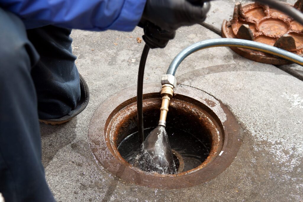 Plumber hydro jetting a sewer line through a manhole in Battleground
