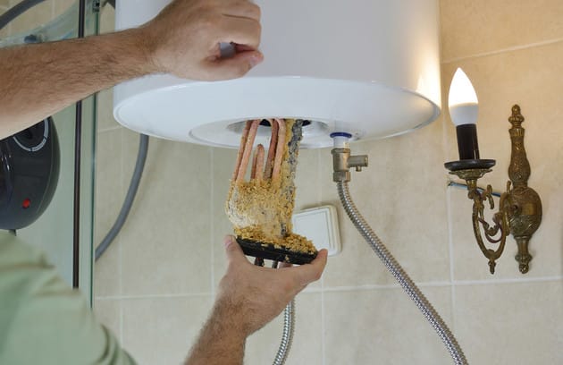 Technician removing mineral buildup from a water heater in Battleground
