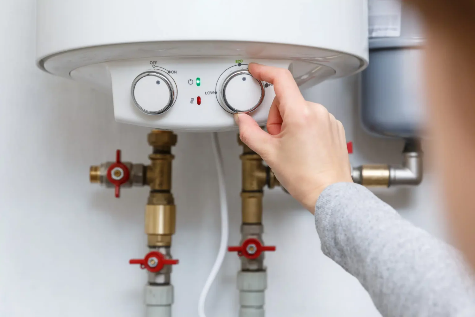 Homeowner adjusting the temperature controls on a water heater in Battleground